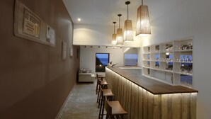 A modern bar area with wooden stools, pendant lighting, and a view of the sea. - The Beach Boutique Hotel (Uswetakeiyawa)