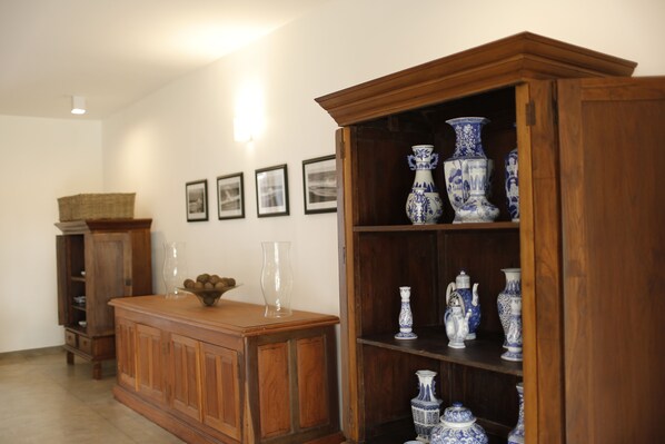 Un meuble en bois doté d’étagères où sont exposés des vases en céramique bleue et blanche, ainsi qu’un vase en verre transparent.