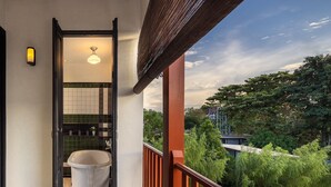 Un balcón con vistas a vegetación y un edificio al fondo.
