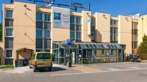 A hotel with a clear entrance, a parking area, and a van parked outside. - ibis Budget Antony Massy (renovated 2024) (Antony)