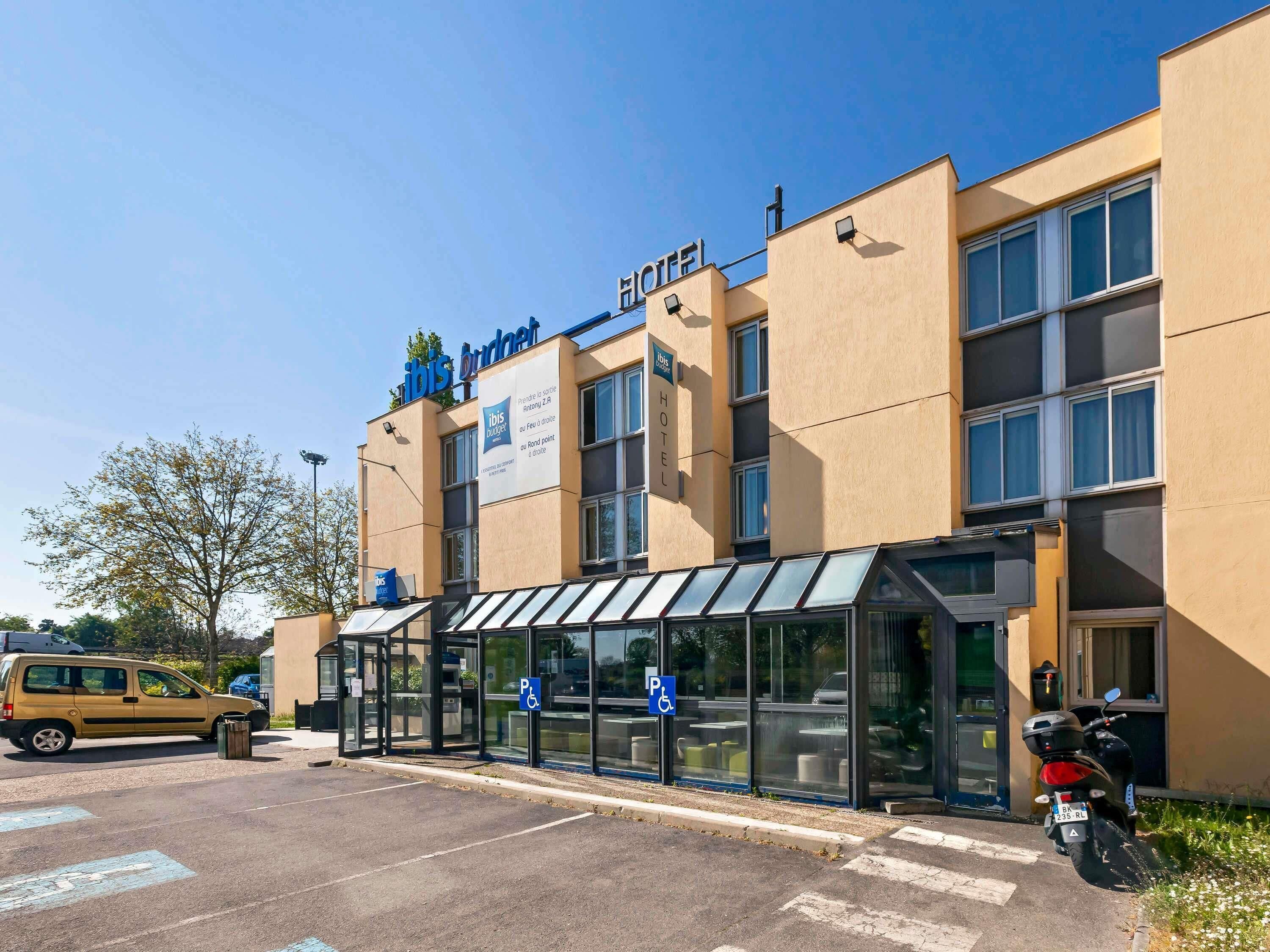 A hotel with a clear entrance, a parking area, and a motorcycle parked outside.