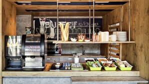 A modern kitchen with a coffee machine, a sink, and various food items displayed on shelves. - ibis Budget Antony Massy (renovated 2024) (Antony)