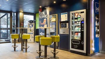 A modern interior with a vending machine, a service kiosk, and yellow stools.