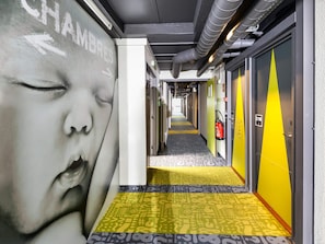 A hotel corridor with a fire extinguisher mounted on the wall, a door with the number 218, and a directional arrow on the wall. - ibis Budget Antony Massy (renovated 2024) (Antony)