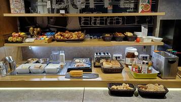 A buffet counter with various food items and condiments.