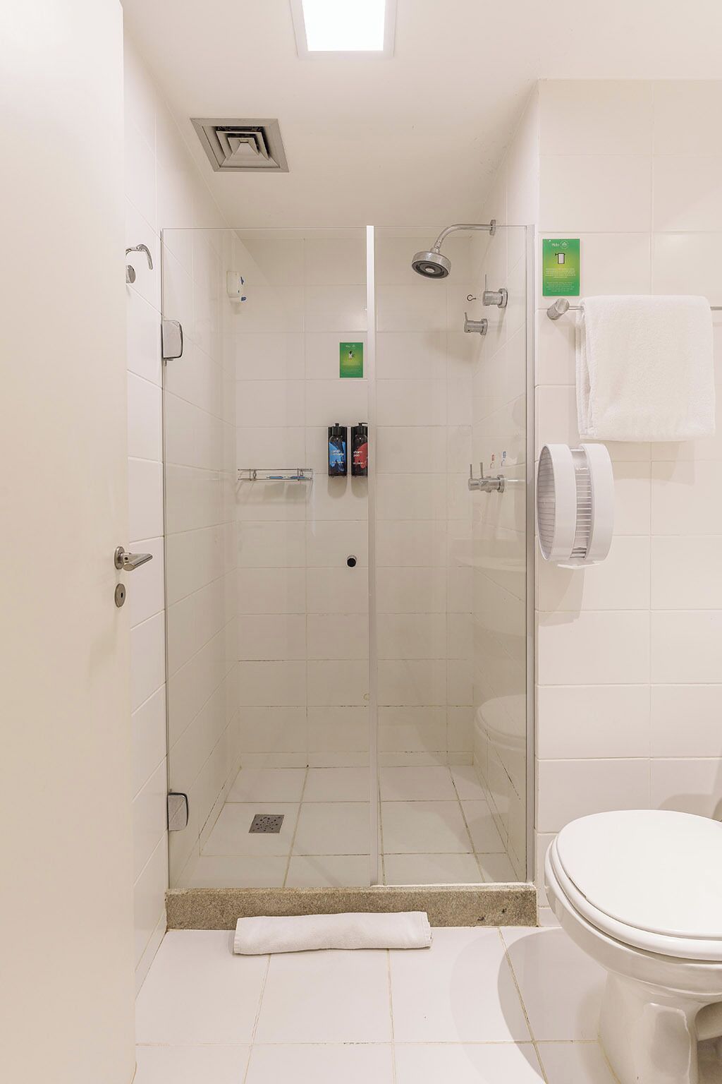 Un box de ducha con paredes de cristal, un inodoro y un perchero en un baño.