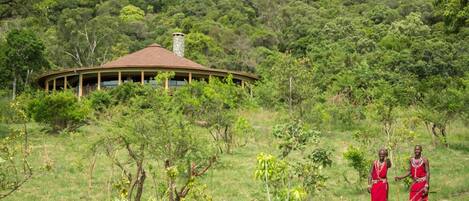 A traditional house with a curved roof surrounded by lush greenery.