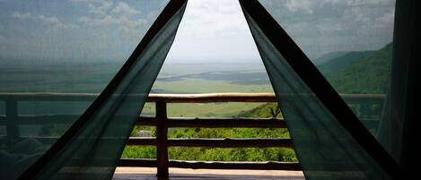 A wooden deck with a view of a green landscape and a clear sky.