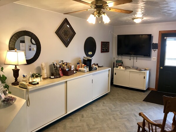 A kitchen with a white refrigerator, a microwave, a stove, and a ceiling fan. There is a window with a view of the outside.