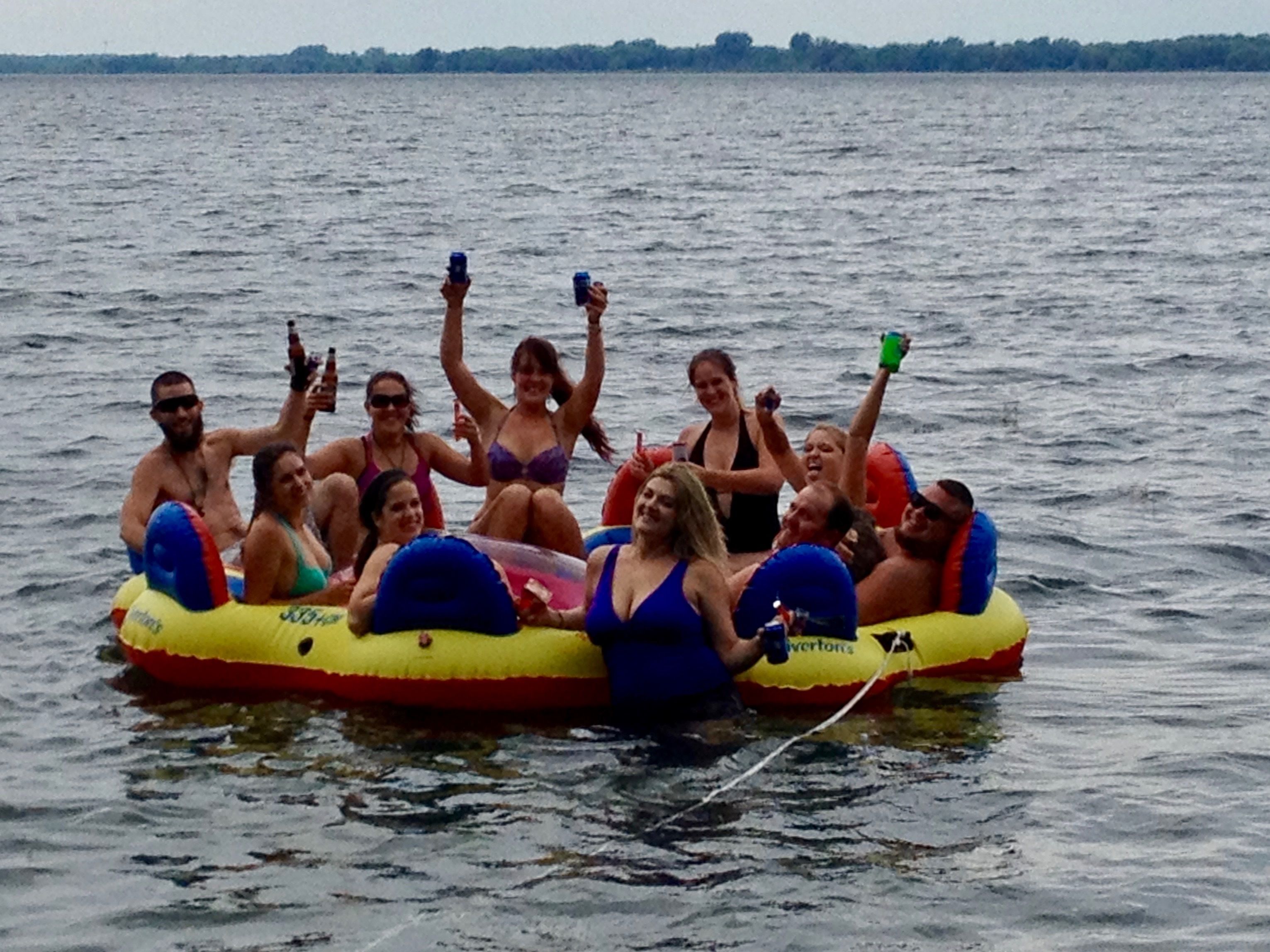 A group of people on a yellow and red inflatable raft floating on water.