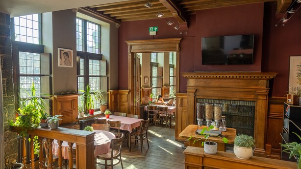 Un restaurant acollidor amb mobiliari de fusta, grans finestres i una llar de foc.