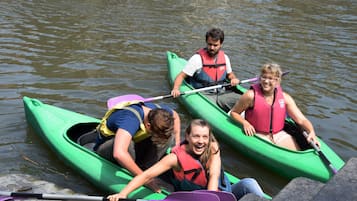 Cuatro personas en kayaks verdes sobre un agua tranquila.