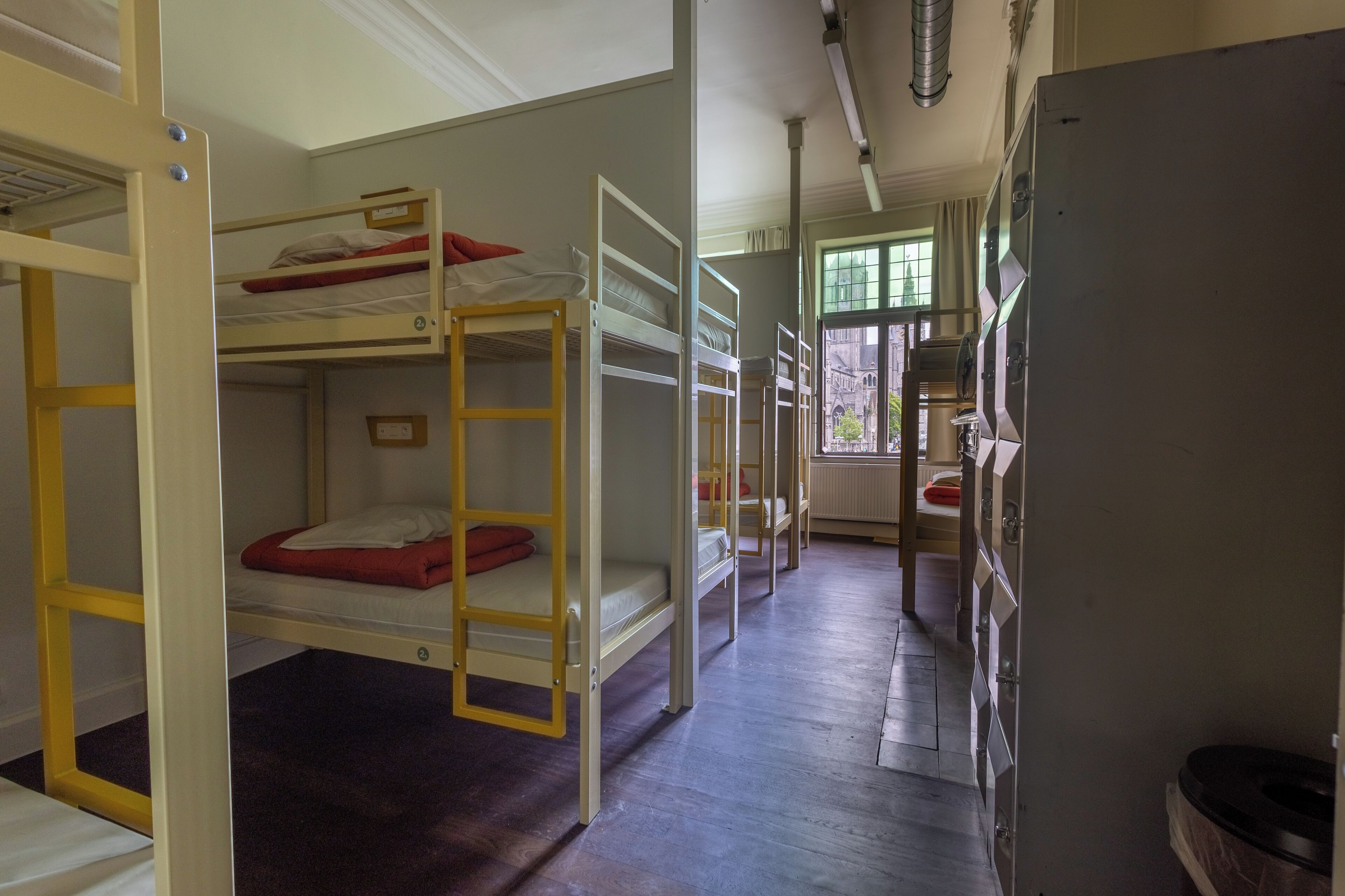 A room with bunk beds, a bathroom with a toilet and sink, and a window with a view of the outside.