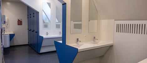 Une salle de bain moderne dotée d’un grand lavabo, d’un miroir et d’un système de ventilation.