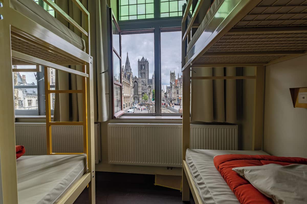 Um quarto tipo dormitório com beliches, vista para a cidade e um radiador.