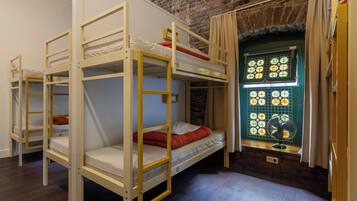 A room with bunk beds, a window with a fan, and a brick wall.