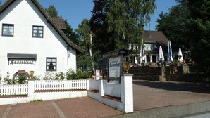 A white building with a sign reading "Hotel/Restaurant Landhaus Sassenhof." - Landhaus Sassenhof (Muelheim an der Ruhr)