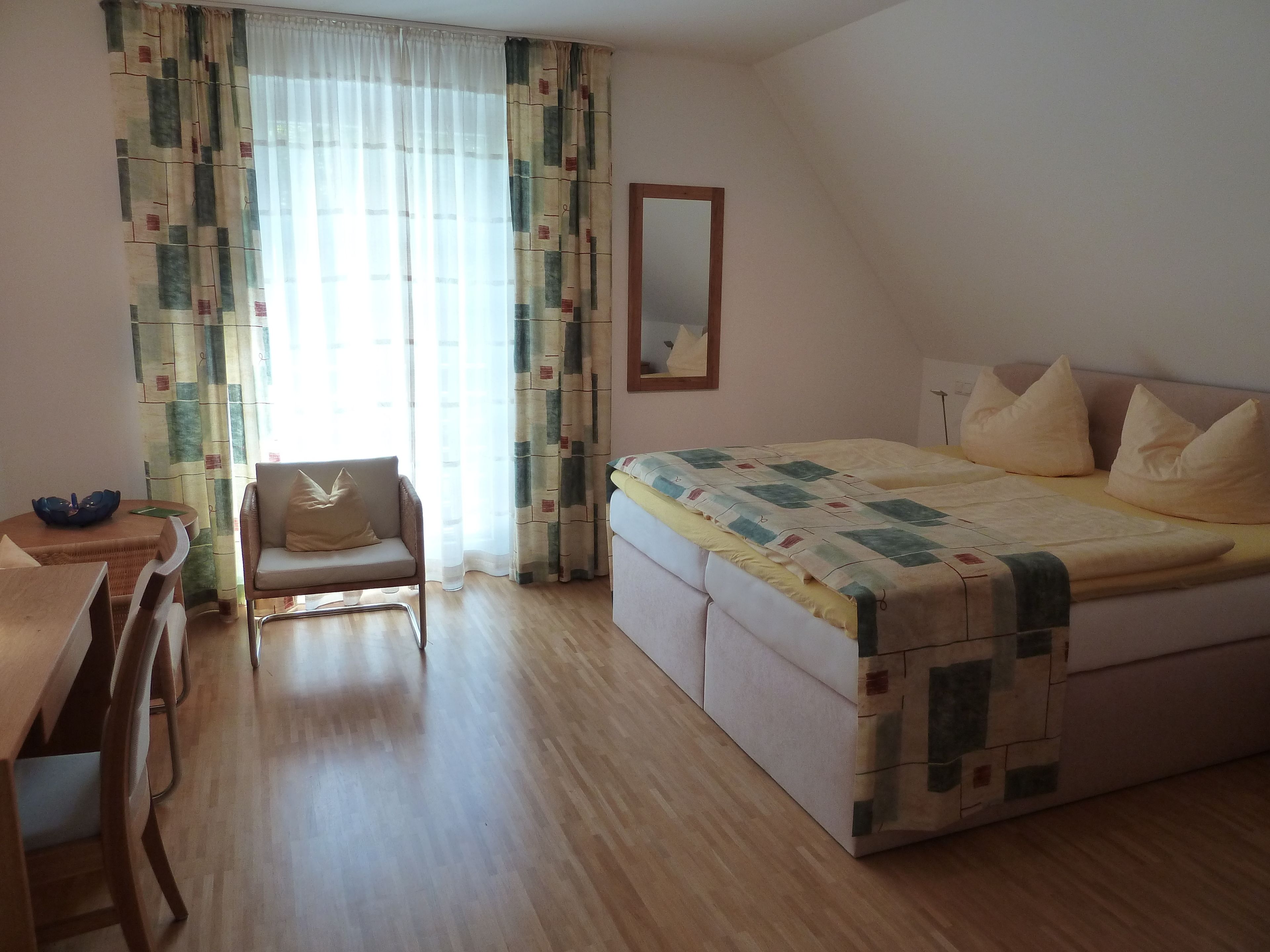 Un dormitorio con cama, una silla, una mesa y un espejo.