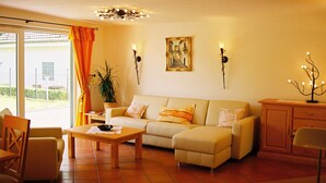 A living room with a sofa, a coffee table, a cabinet, and a potted plant. - Landhaus Sassenhof (Muelheim an der Ruhr)