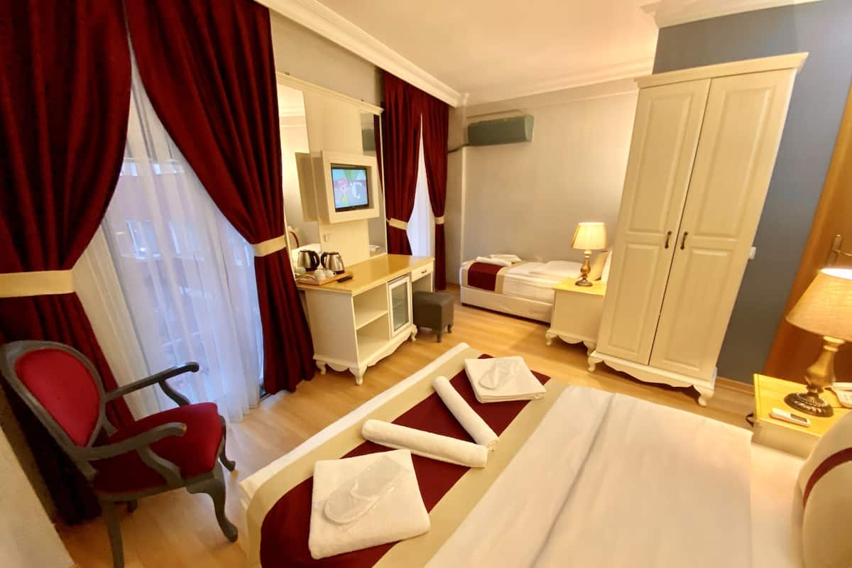 A hotel room with a bed, a desk, a chair, a wardrobe, and a TV.