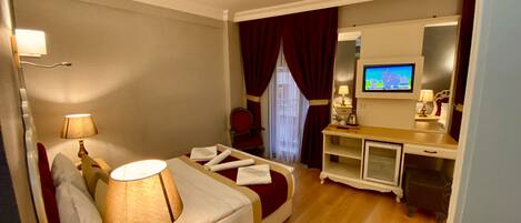 A hotel room with a bed, bedside lamps, a desk with a television, and a mirror.