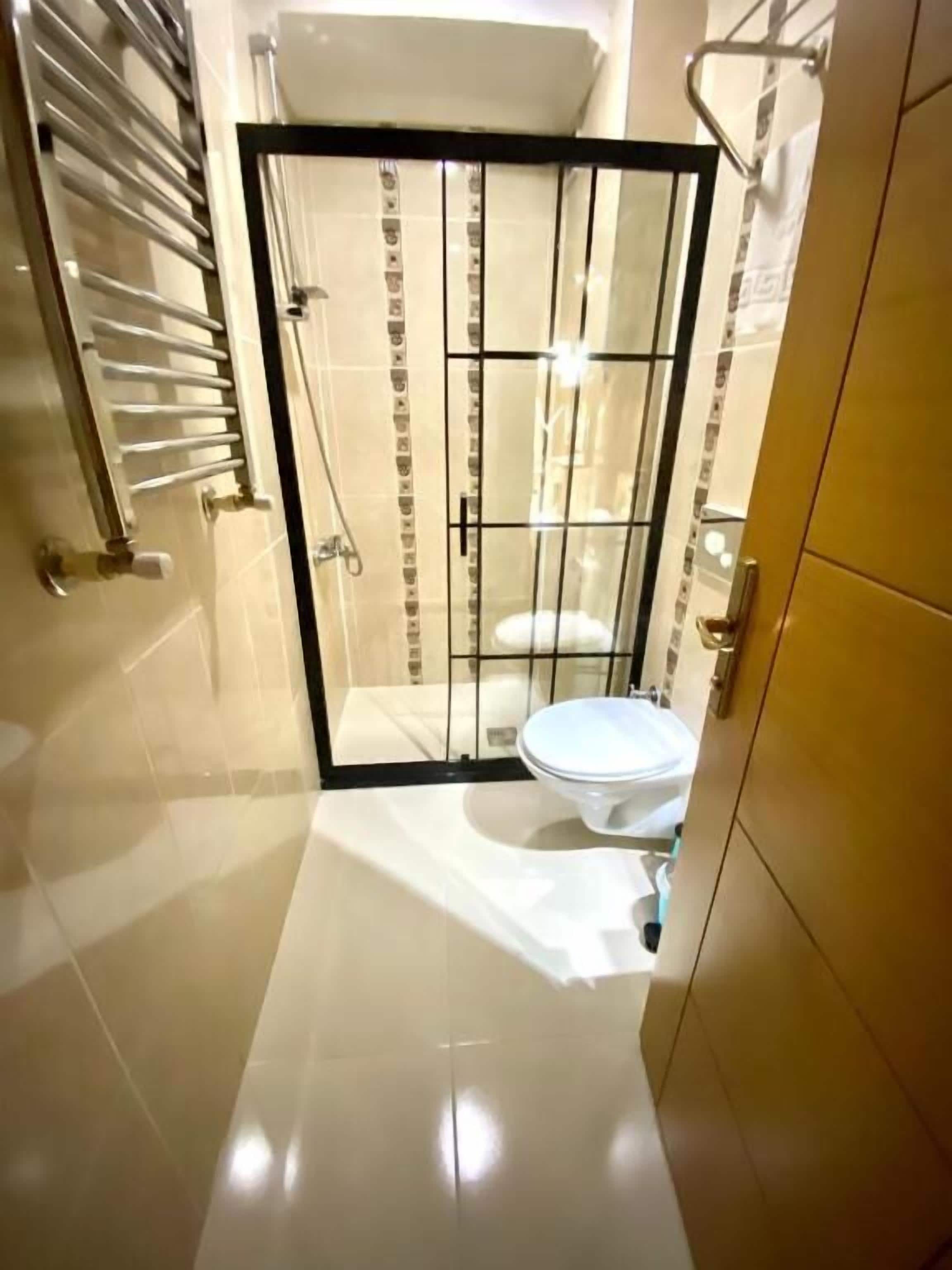 A bathroom with a shower enclosure, toilet, and a towel rack.