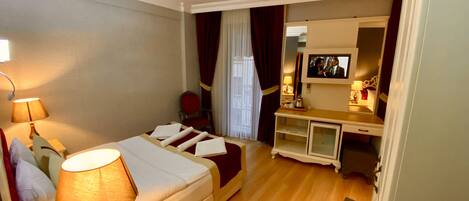 Habitación de hotel con cama, mesita de noche, lámpara, escritorio, silla y televisión.