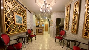 A lobby with marble flooring, red upholstered chairs, and decorative wall panels. - Santefe Hotel (Istanbul)