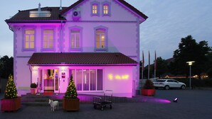 A two-story building with a red-tiled roof and a balcony. - Hotel Villa Will (Isernhagen)
