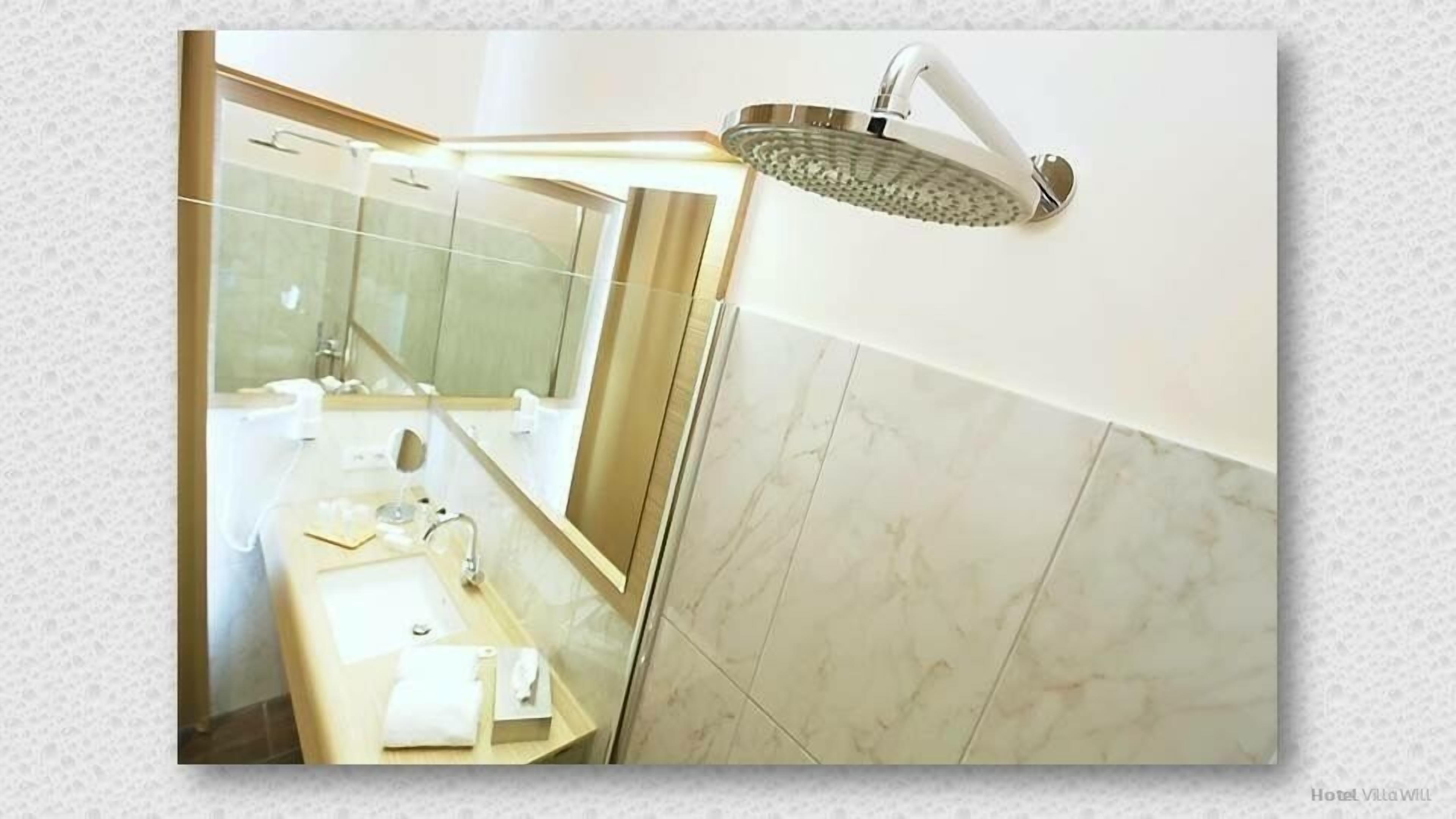 A bathroom with a large mirror, a sink, and a shower head.