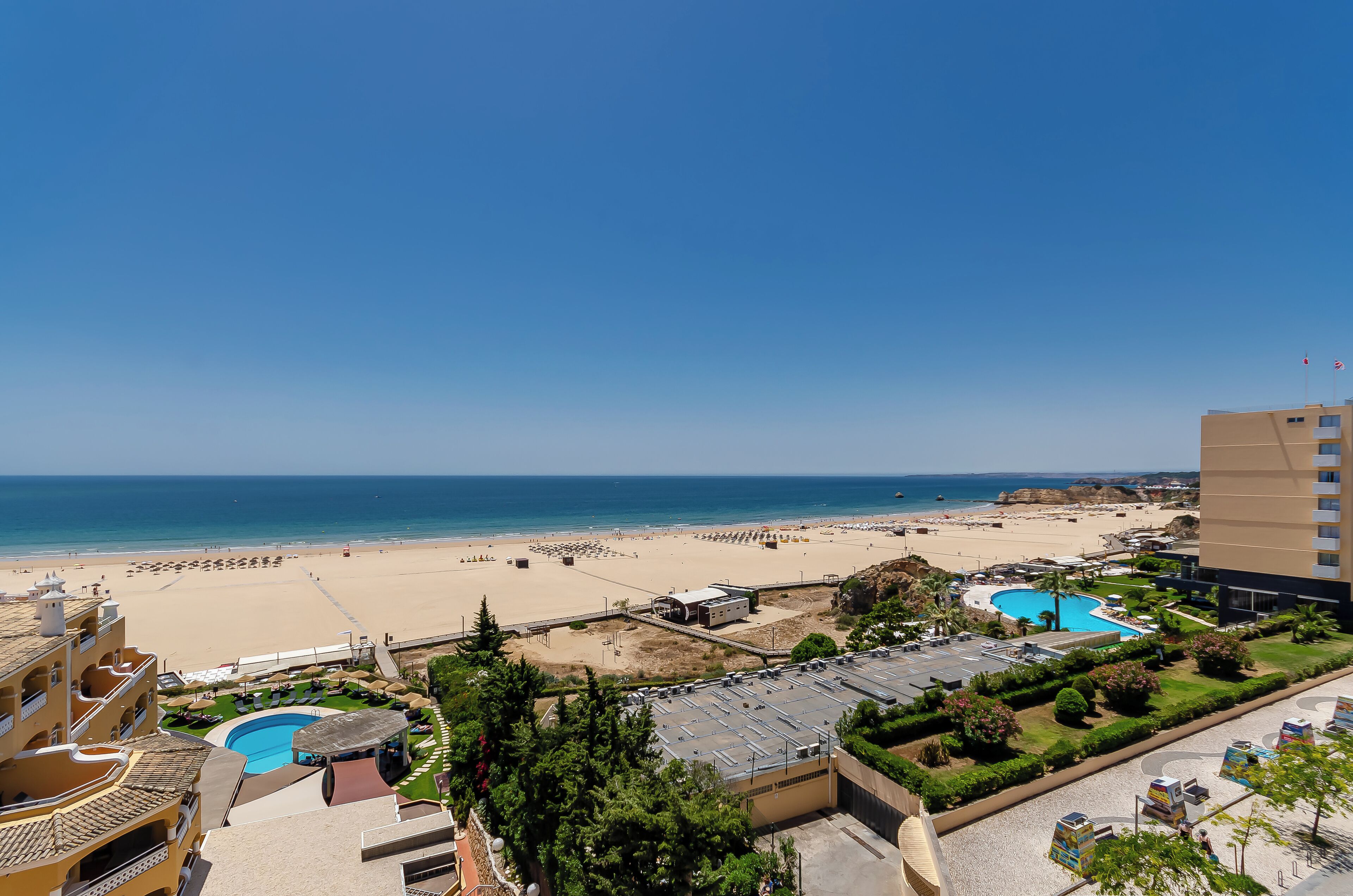 Un resort con varias piscinas, una playa y vista al mar.