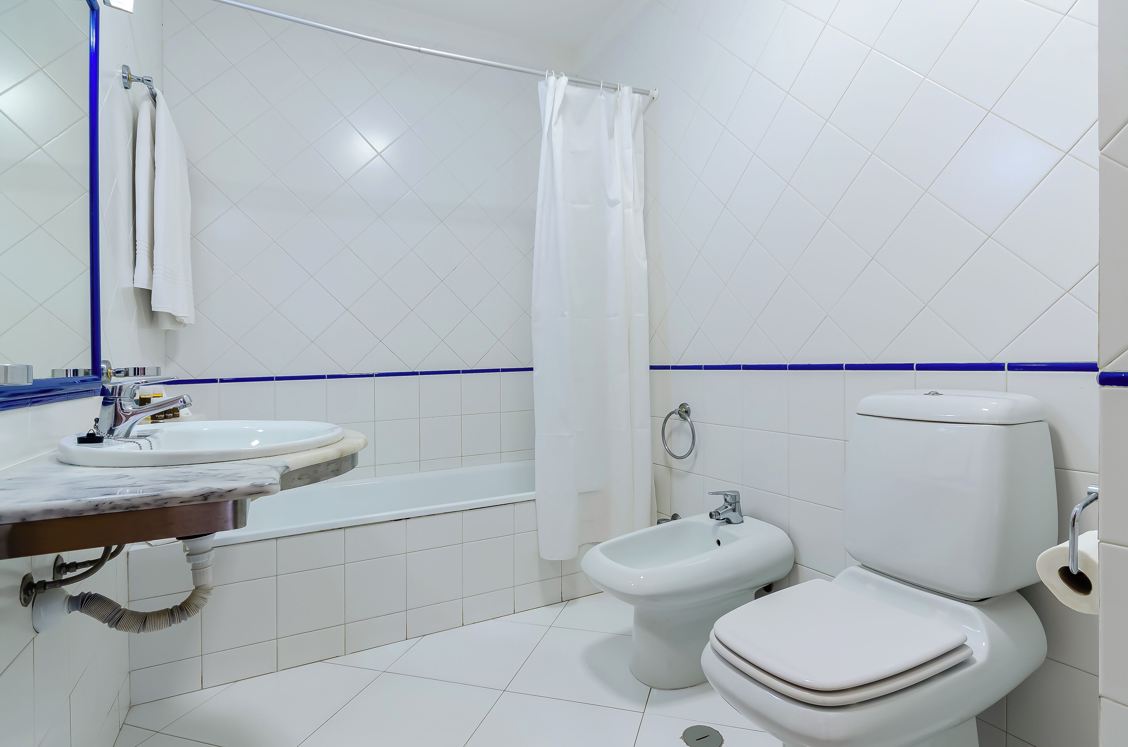 A bathroom with a white sink, a bidet, and a toilet.