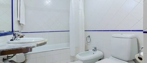 A bathroom with a white sink, a bidet, and a toilet.