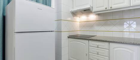 Una cocina con armarios blancos, un refrigerador y una encimera.