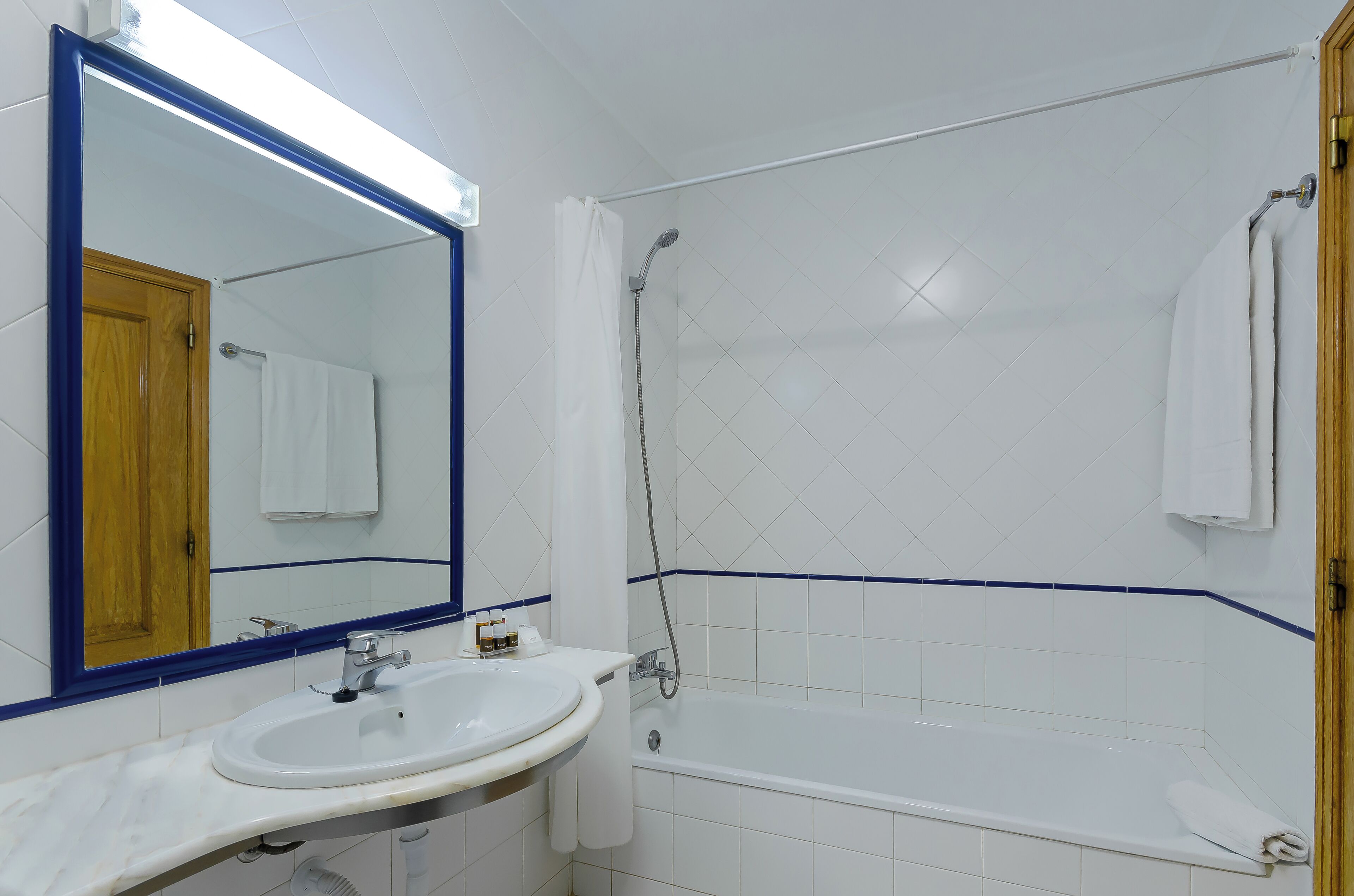 A bathroom with a white sink, mirror, and bathtub.