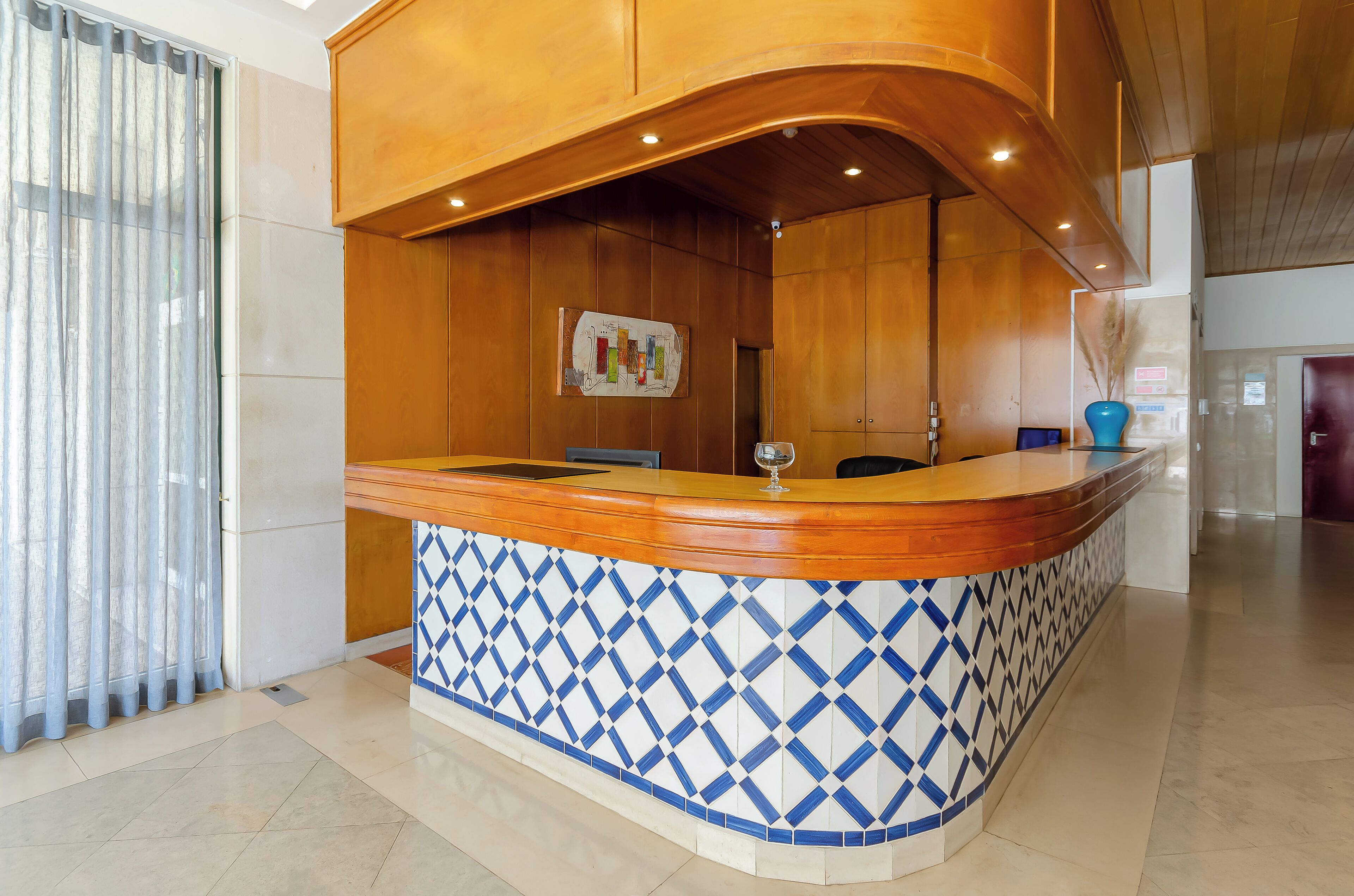 A reception area with a wooden counter, blue and white patterned tiles, and a map on the wall.