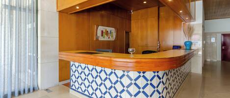 A reception area with a wooden counter, blue and white patterned tiles, and a map on the wall.