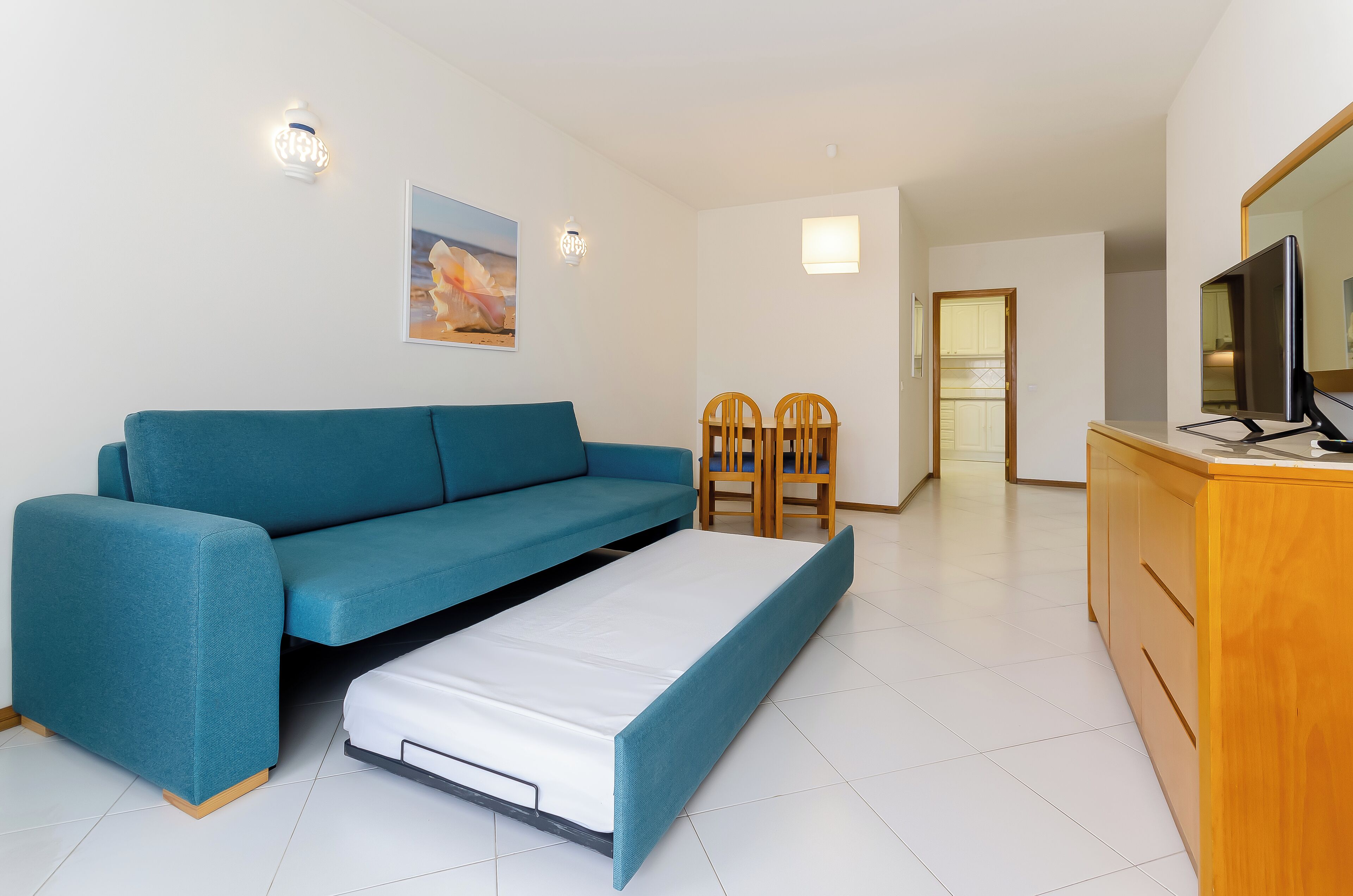 Un espace de vie compact comprenant un canapé, une petite table et un téléviseur.