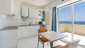 A modern kitchen with white cabinets, a microwave, and a table with chairs. - TURIM Algarve Mor Hotel (Portimão)