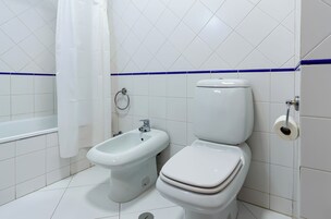 A bathroom with a bidet, toilet, and bathtub.
