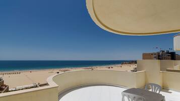 A balcony with a view of a beach and the sea.