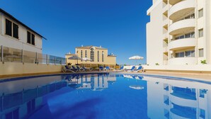 A swimming pool with lounge chairs and a building in the background. - TURIM Algarve Mor Hotel (Portimão)