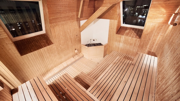 Interior de madera con dos ventanas, techo inclinado y tragaluz central.