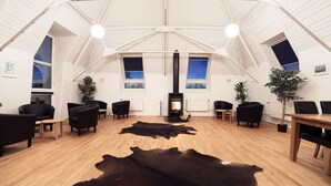 Un loft espacioso con techos altos, una chimenea central y un gran tapete de cuero negro sobre el piso de madera.