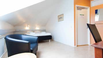 Een slaapkamer met een bed, een stoel, een bureau en een raam.