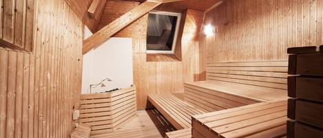 A sauna with wooden benches and a sloped ceiling.