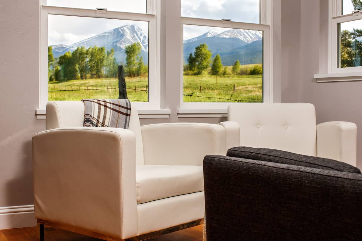 Ein Wohnzimmer mit Blick auf eine Berglandschaft durch große Fenster.
