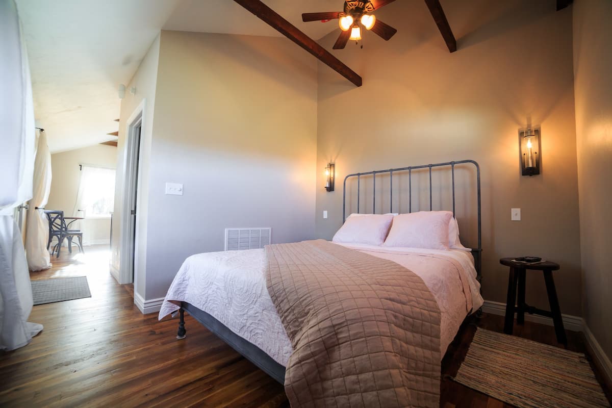 Ein Schlafzimmer mit Bett, Deckenventilator, Nachttisch und Fenster.
