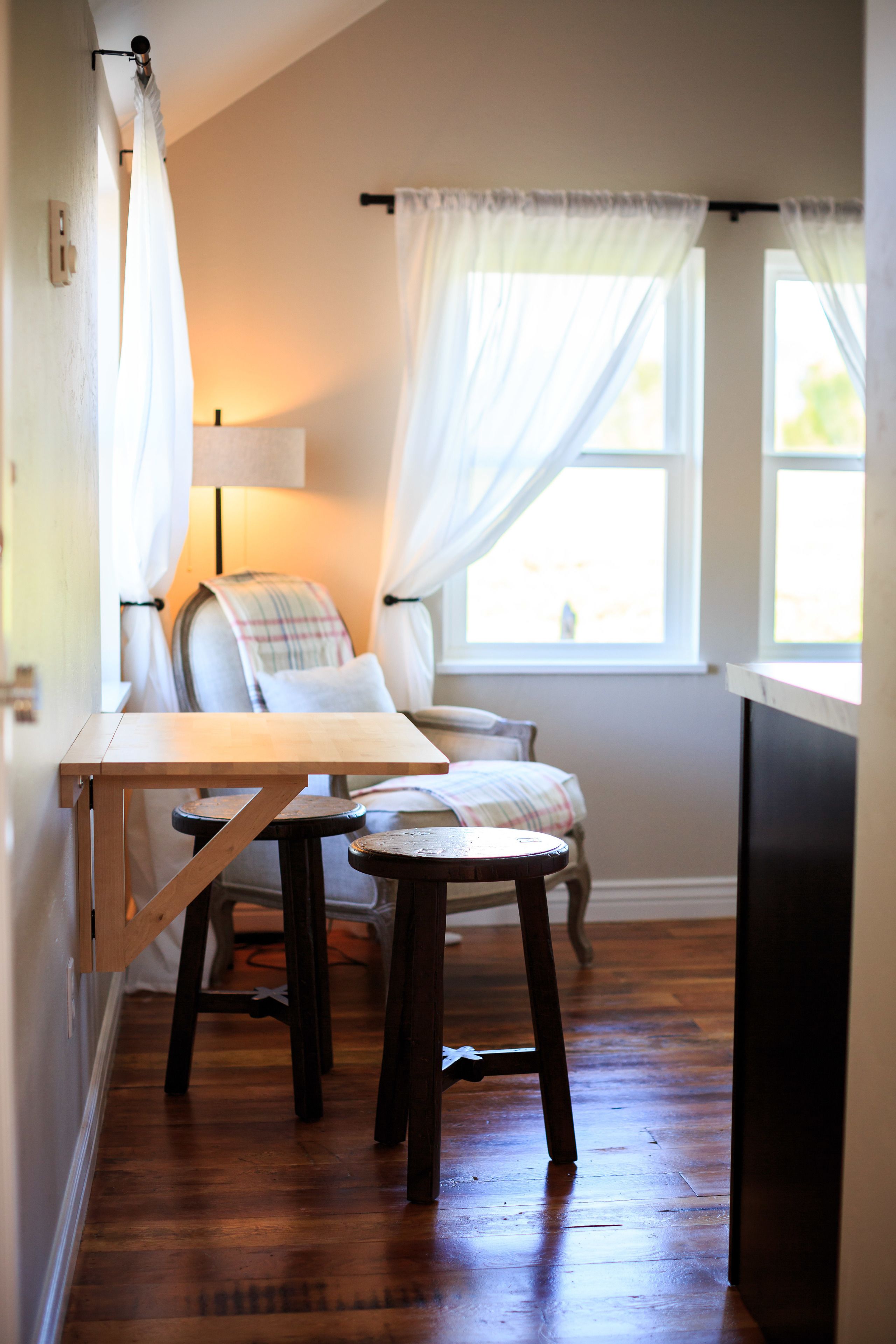 Una habitación acogedora con una mesa de madera, dos sillas, un sofá y una ventana con cortinas.