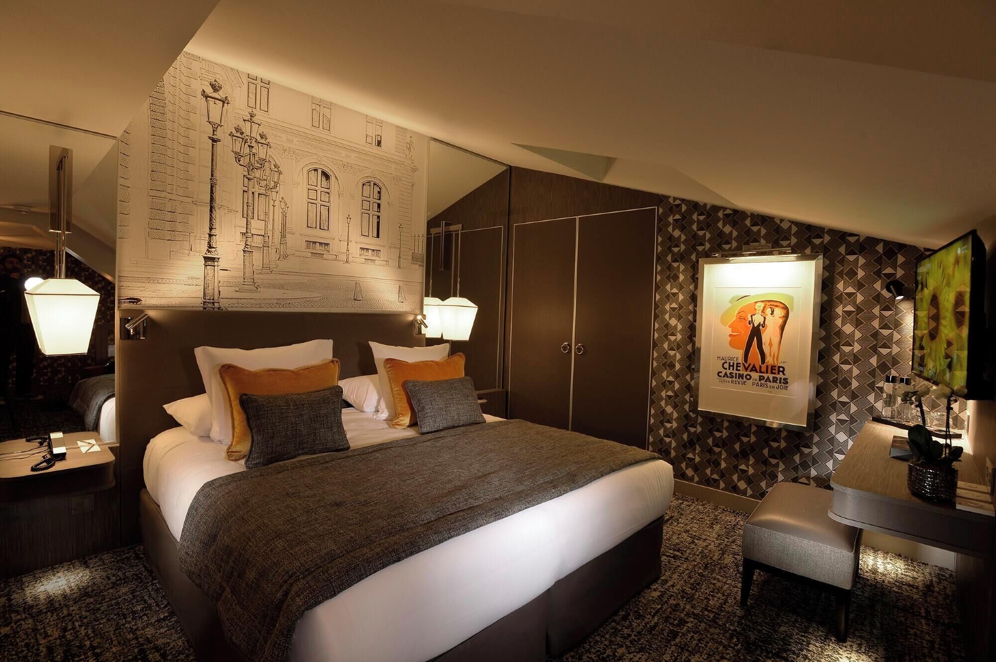 A hotel room with a large bed, dark wood wardrobe, a desk with a chair, and a poster on the wall.